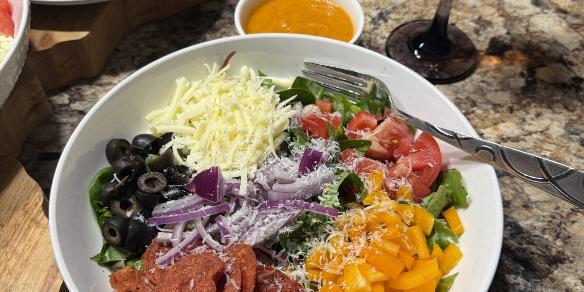 Pizza salad with pepperoni, peppers, cheese, and sun dried tomato vinaigrette